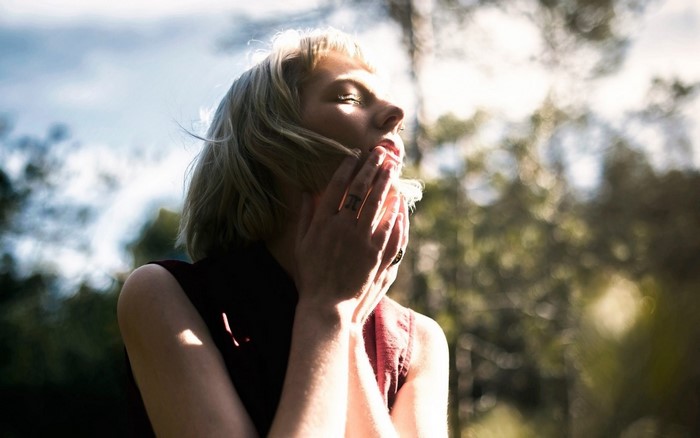 Woman with hands on face in sunlight