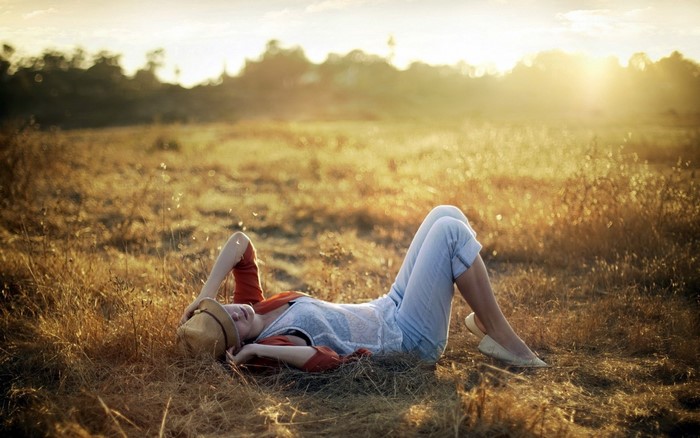 Woman lying in a field at sunset