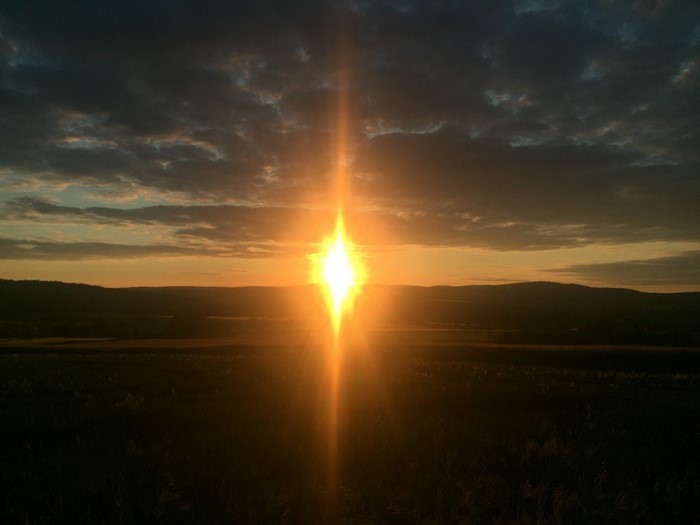Sunset over rolling hills with dramatic clouds