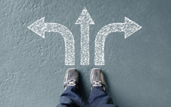 Person standing at a crossroads with three arrows