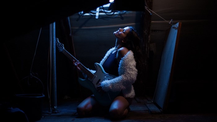 Woman playing guitar in a dark room