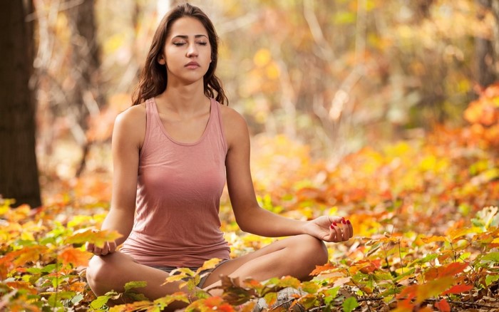 Woman meditating in a fall forest