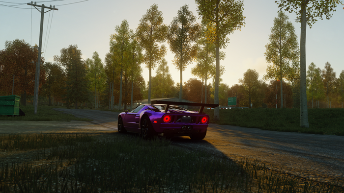 Purple Ford GT 2005 driving on a road at sunset