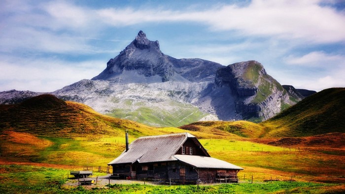 Wooden cabin in a mountain valley with a sharp peak