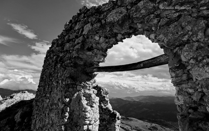 Stone Arch Ruin with Wooden Beam and Mountain Landscape