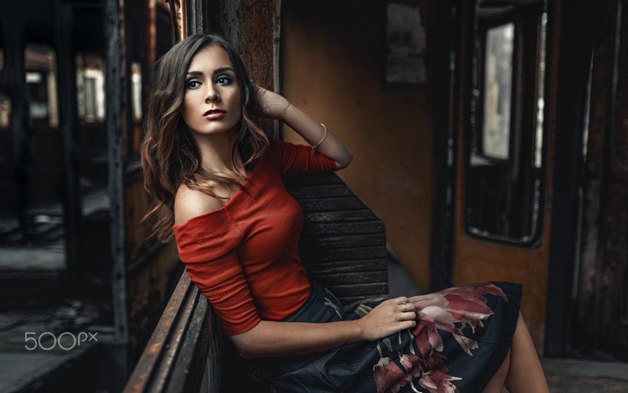 Woman with long hair in a red top and floral skirt