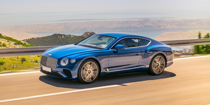 Blue Bentley Continental GT driving on a mountain road