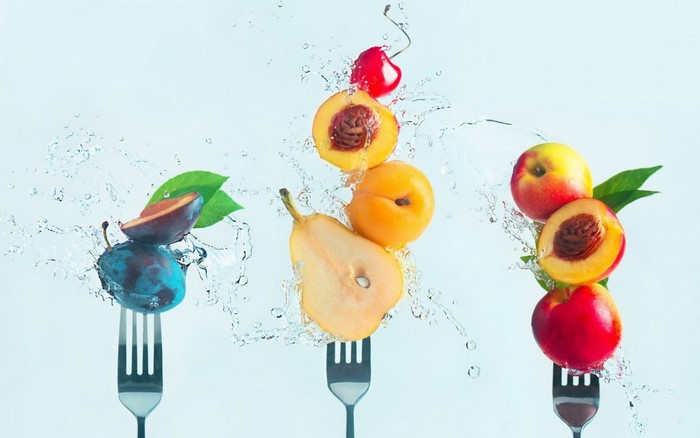 Fruits on forks with water splashes