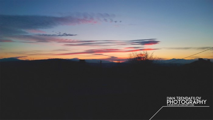 Sunset over a silhouetted landscape with colorful clouds