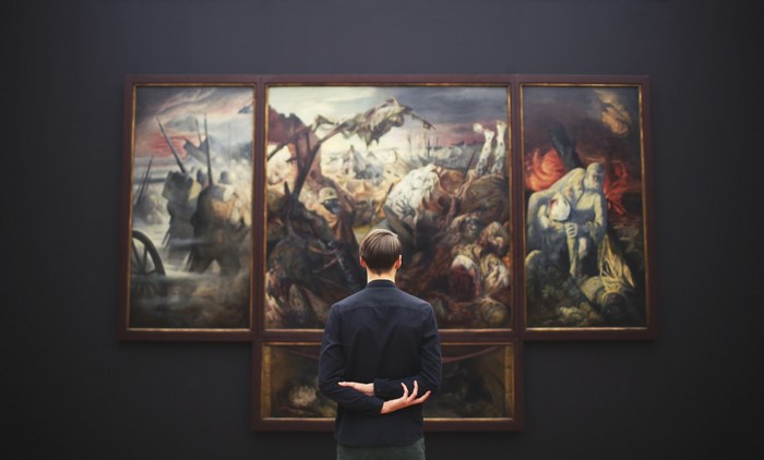 Man viewing a triptych painting in an art gallery