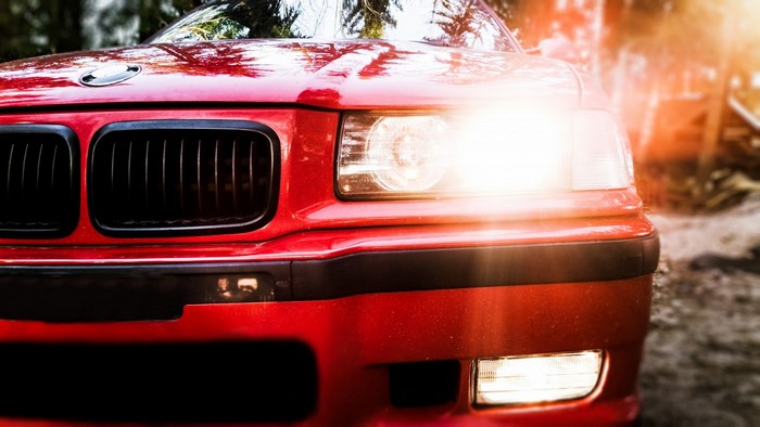 Red BMW E36 M-Sport car with headlights on
