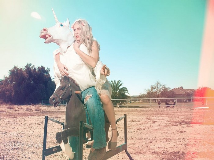 Woman with unicorn mask on rocking horse