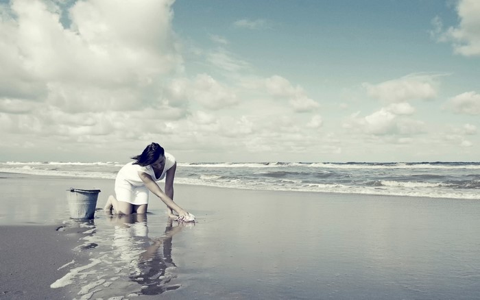 Woman cleaning the beach with a bucket and cloth