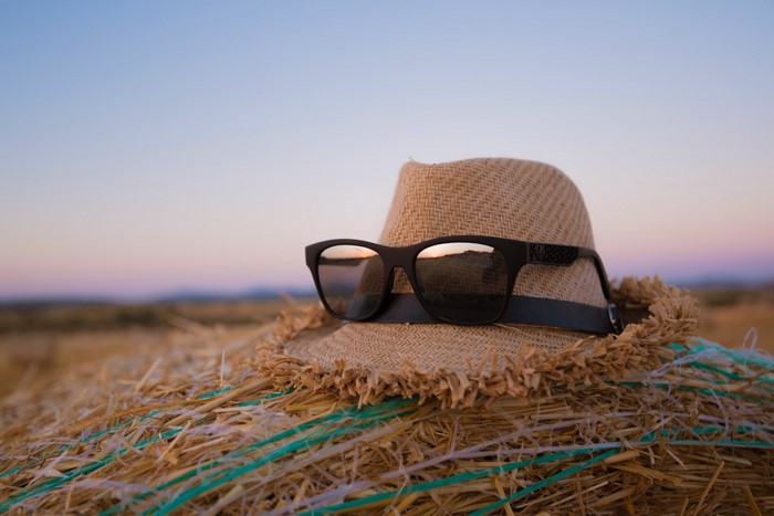 Straw hat and sunglasses on a hay bale at sunset
