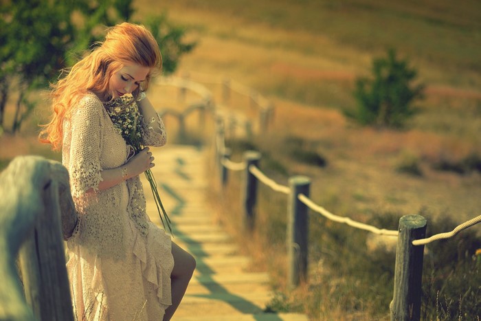 Redhead woman holding flowers on a wooden path