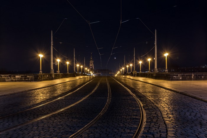 Tram tracks on a cobblestone bridge at night