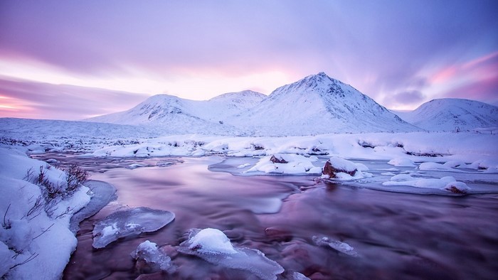 Snowy mountains and river at sunrise