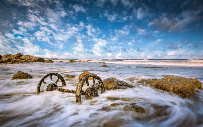 Rusty metal wheels in the ocean waves