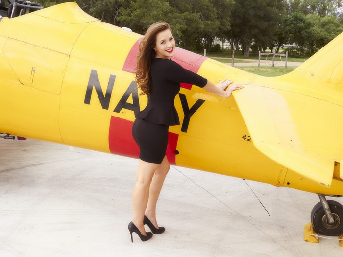 Woman posing next to a yellow Navy airplane