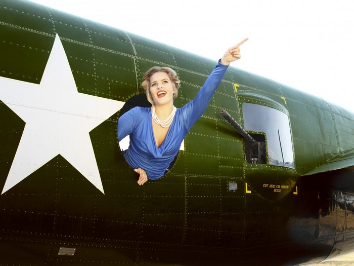 Woman in blue dress pointing from airplane window