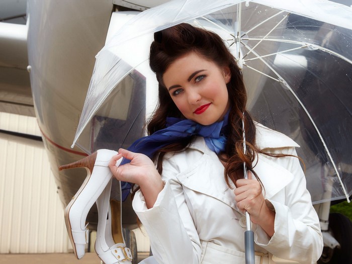 Woman with umbrella and shoes near airplane