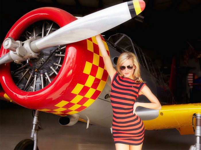 Woman posing with a vintage airplane