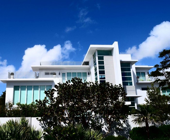 Modern white mansion with balconies and blue sky
