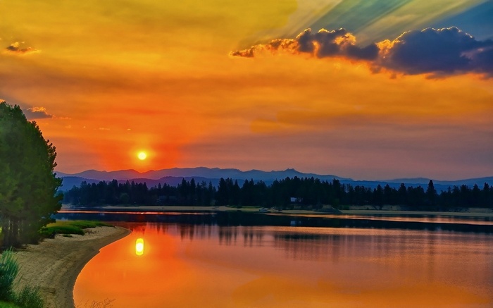Sunset over a lake with mountains and trees
