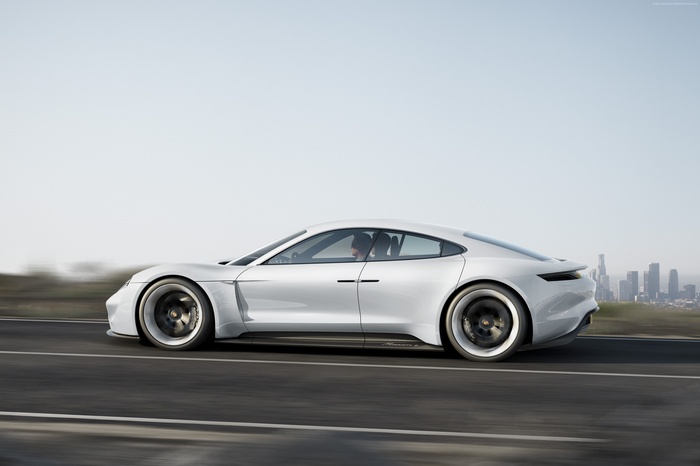 White Porsche Taycan driving on a road with city skyline