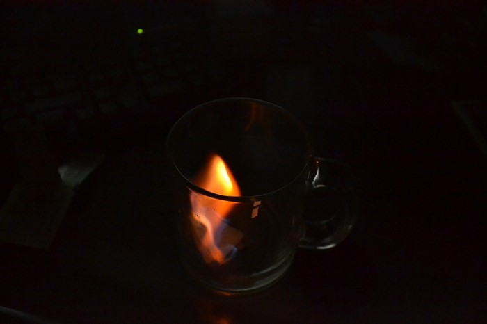 Flame inside a glass mug in darkness