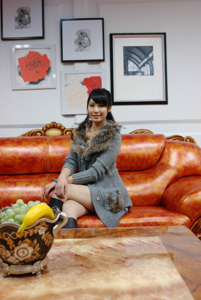 Woman sitting on a leather couch with paintings on the wall