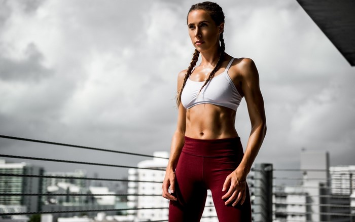 Woman in sports bra and leggings posing outdoors