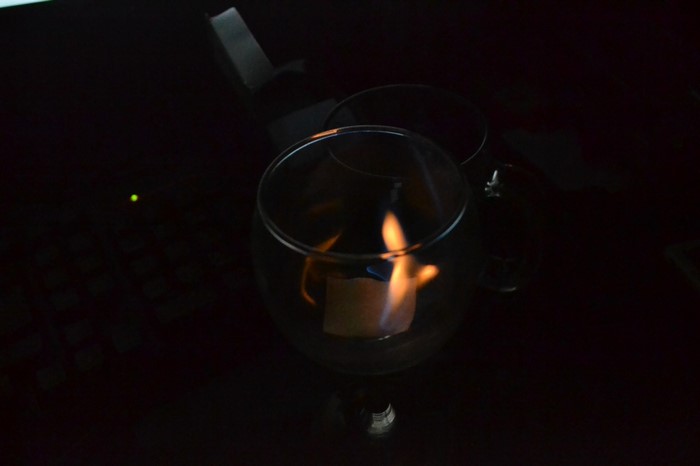 Candle flame inside a glass holder on a dark surface