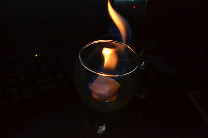 Flame burning in a glass on a dark surface
