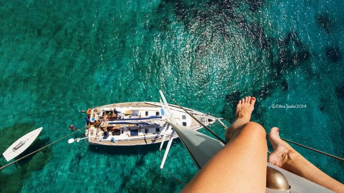 Woman's legs over a sailboat in turquoise water