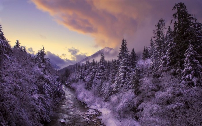 Snowy mountain valley with river at sunset