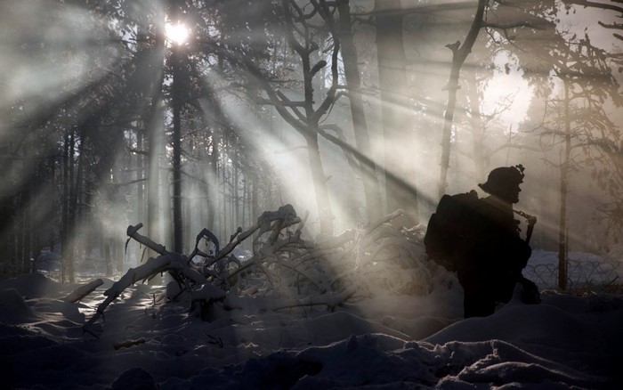 Soldier in a snowy forest with sun rays