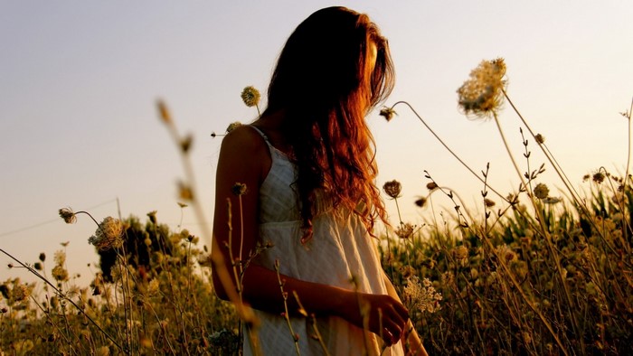 Woman in a white dress in a field at sunset
