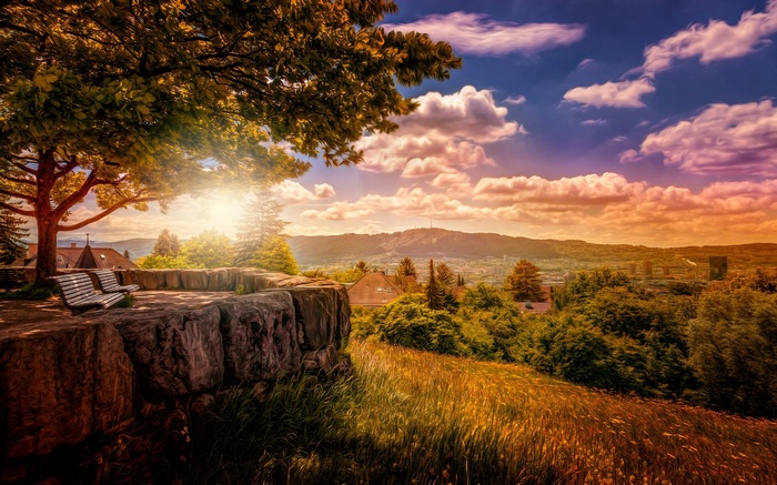 Scenic overlook with benches and a distant city view at sunset