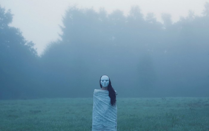 Woman in mask in foggy field