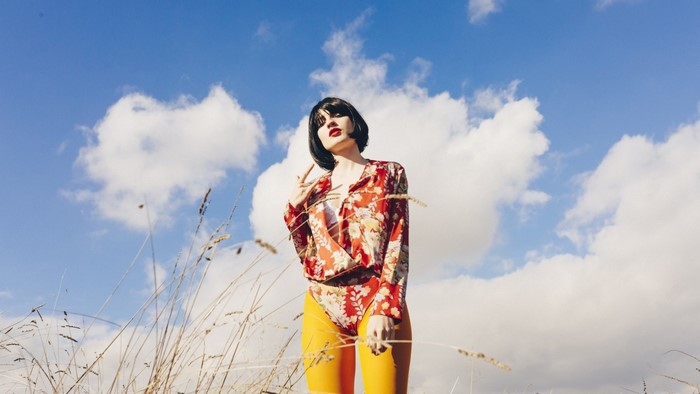 Woman in floral bodysuit and yellow tights outdoors