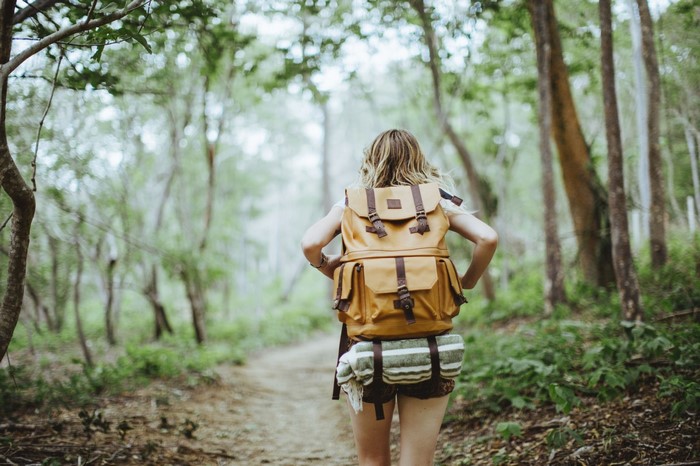 Woman with backpack hiking in a forest