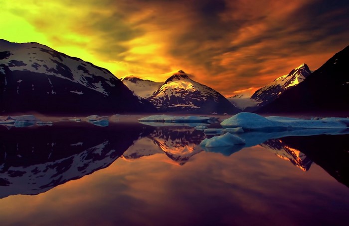 Snow-capped mountains reflected in a lake at sunset