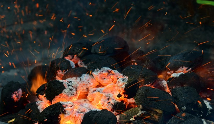 Close-up of glowing hot coals with sparks