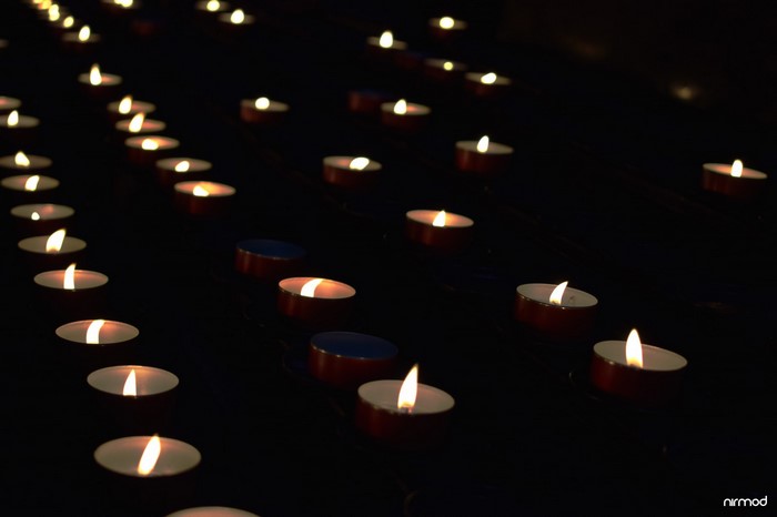 Rows of lit candles in darkness
