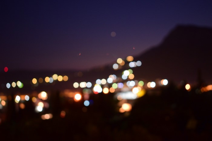 Blurred city lights at night with mountain silhouette