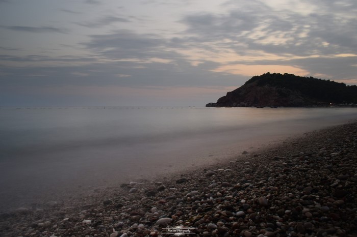 Pebble beach at dusk with a hill overlooking the sea