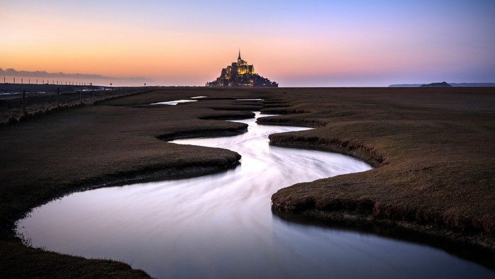 Mont Saint Michel at sunset with winding river