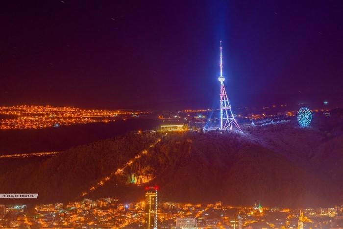 Tbilisi cityscape at night with TV tower and Ferris wheel