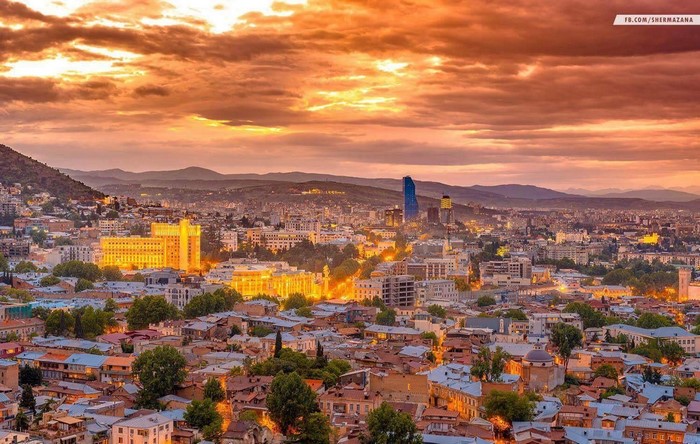 Cityscape of Tbilisi, Georgia at sunset with dramatic clouds